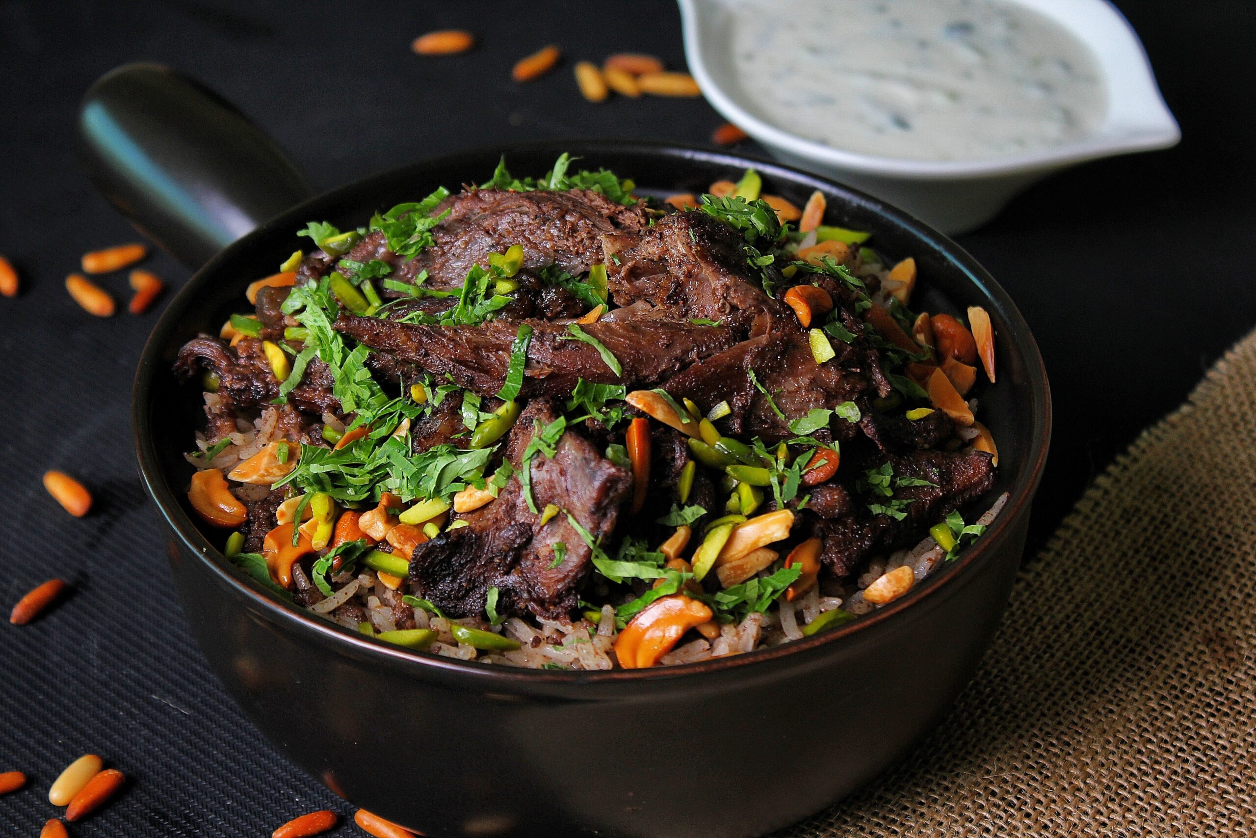 A delicious serving of spiced meat with rice, nuts, and herbs in a bowl.
